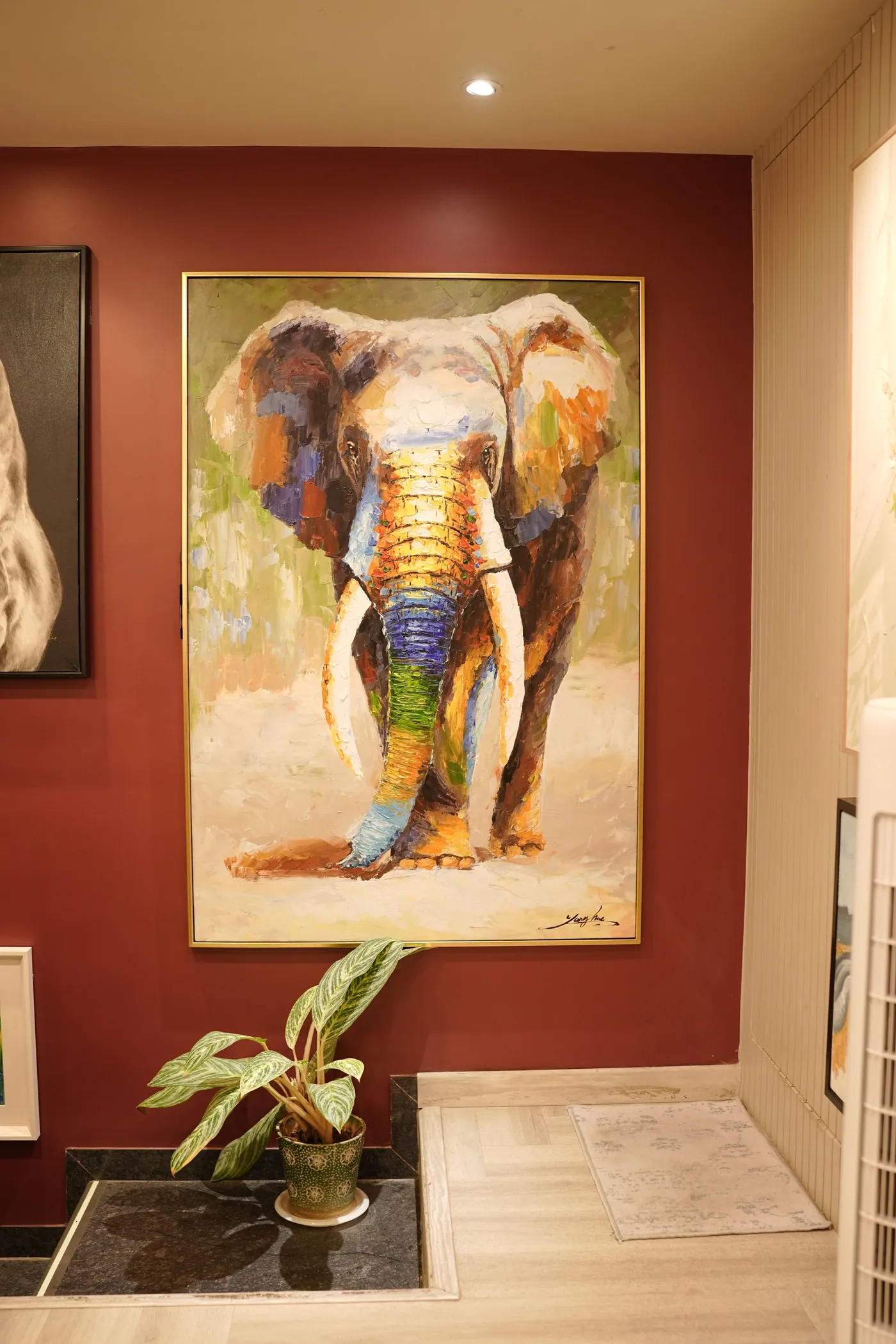 Impasto elephant painting on a claret wall in a slim gilt frame