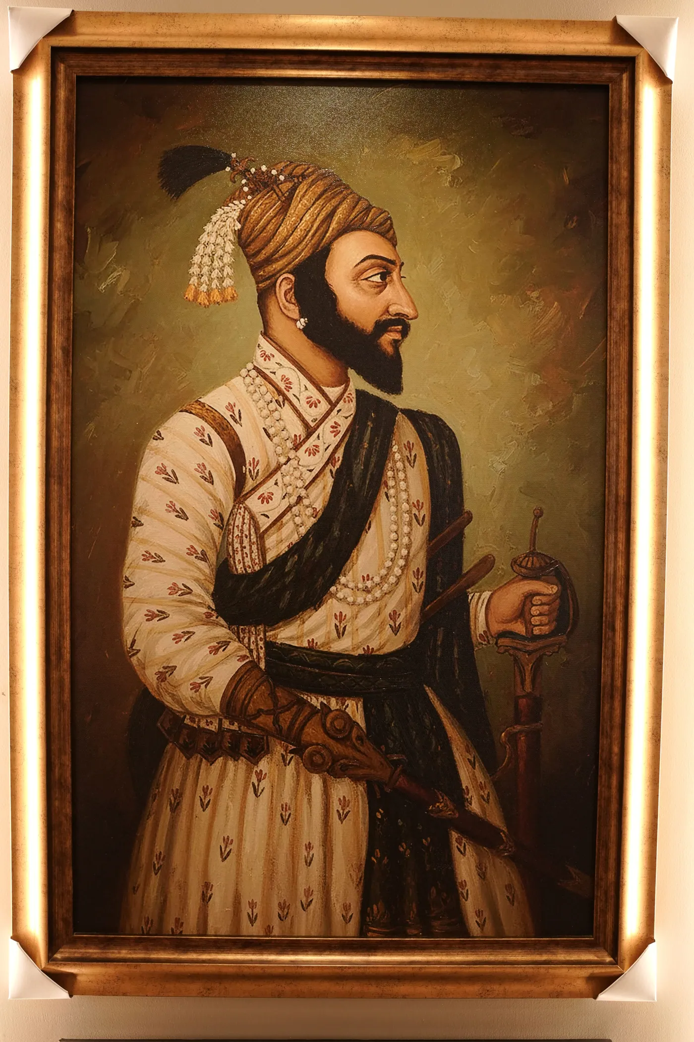 Portrait in oil framed in ornate gilt, lit on the showroom wall